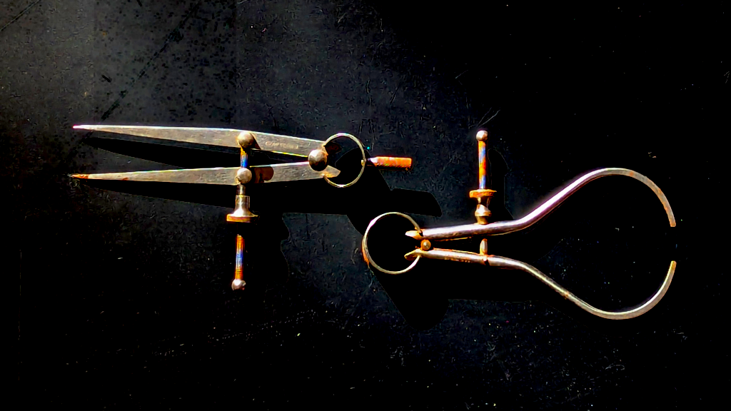 Image of two machinist's calipers. The calipers are bright metal, slightly rusted, and appear against a black background.