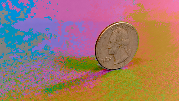 A quarter coin is balancing on its edge on a colorful background