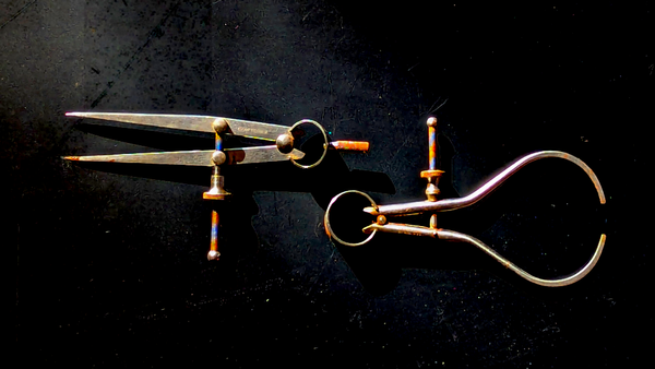 Image of two machinist's calipers. The calipers are bright metal, slightly rusted, and appear against a black background.